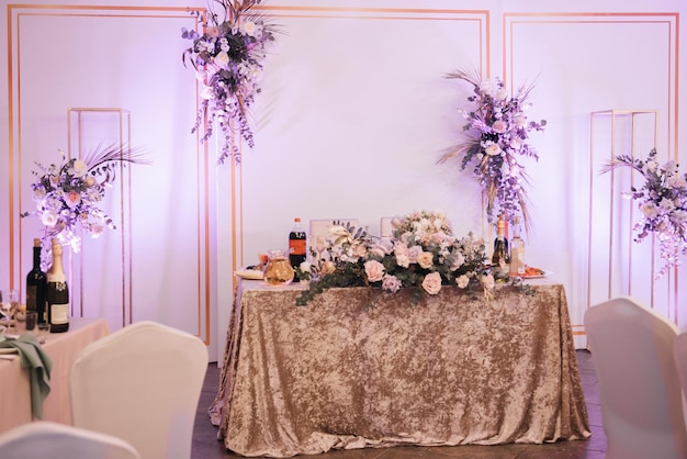 La mesa del presidium para los recién casados está decorada con un mantel de terciopelo y arreglos florales.