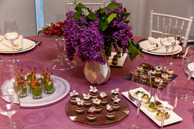 Mesa redonda com toalha rosa e talheres com petiscos para o banquete. catering, mesas de servidor para bonquet