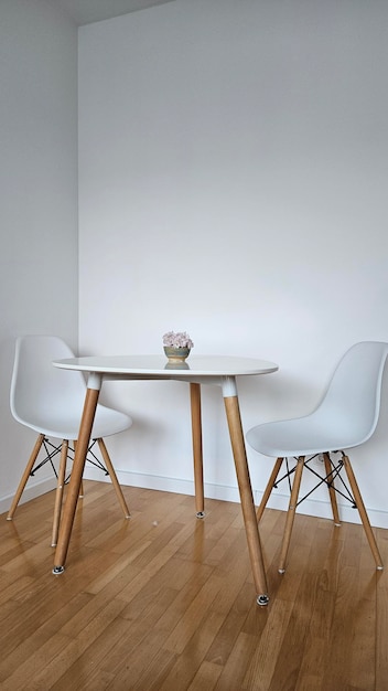 Mesa redonda en el interior con suelo de parquet y pared blanca