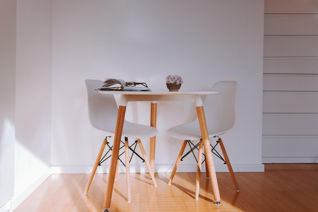 Mesa redonda en el interior con suelo de parquet y pared blanca