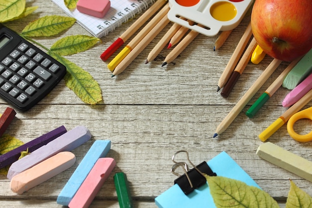 Mesa de regreso a la escuela con hojas de otoño y papelería de diferentes útiles escolares