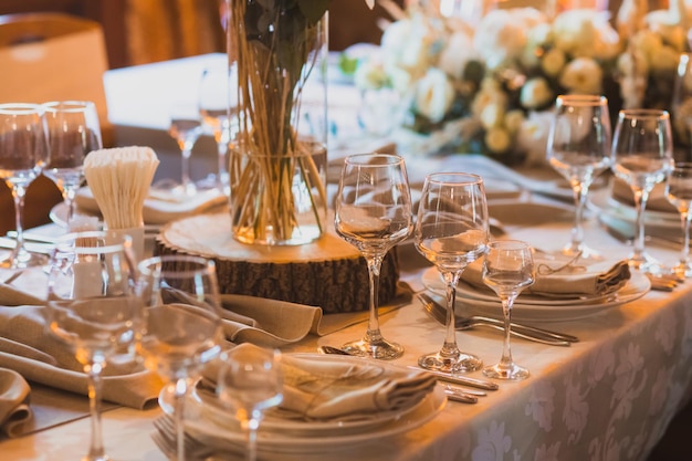 Mesa requintadamente servida para festa de casamento Pedaço de tronco de madeira usado como suporte para vaso de vidro colocado no meio da mesa Toalha de mesa e guardanapos feitos de materiais naturais Design biofílico