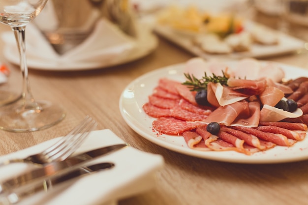 Mesa en el restaurante con bocadillos de carne, cubiertos, copas de vino.