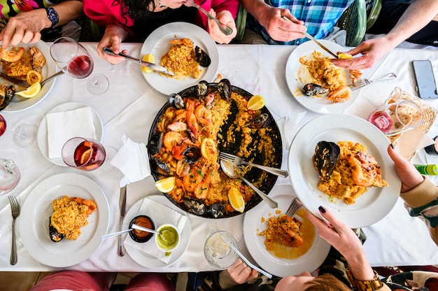 La mesa en el restaurante con paella española con mariscos servidos en una sartén. Camarones frescos, cigalas, mejillones, calamares, pulpos y vieiras. Vista superior. Restaurante