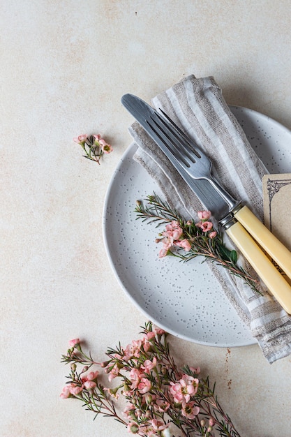 Mesa romântica ou de primavera Faca e garfo pequenas flores cor de rosa e guardanapo de linho em um prato