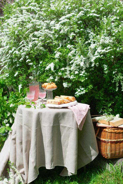 Mesa romántica de primavera festiva con postre en el jardín de flores concepto de mesa romántica vertical