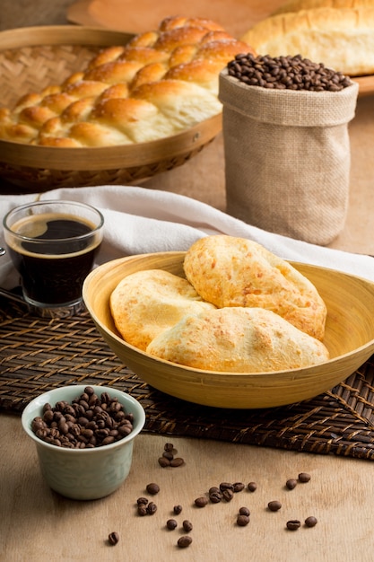 Mesa rústica com vários tipos de pães, grãos torrados e uma xícara de café