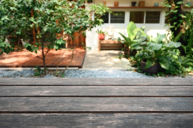 Mesa rústica de madera marrón sobre una planta verde borrosa en el patio trasero del jardín en el soleado