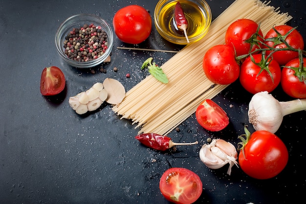 Mesa rústica negra con rama de tomates y hierbas, vista superior