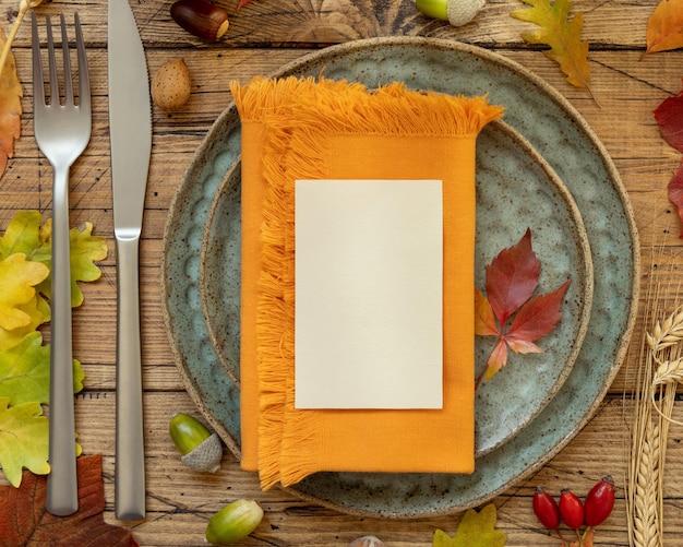 Mesa rústica de otoño con tarjeta de lugar y sobre entre hojas y maqueta de vista superior de bayas