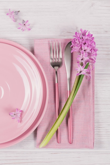 Mesa rústica rosa com flor de jacinto roxo e guardanapo de linho na mesa de madeira branca