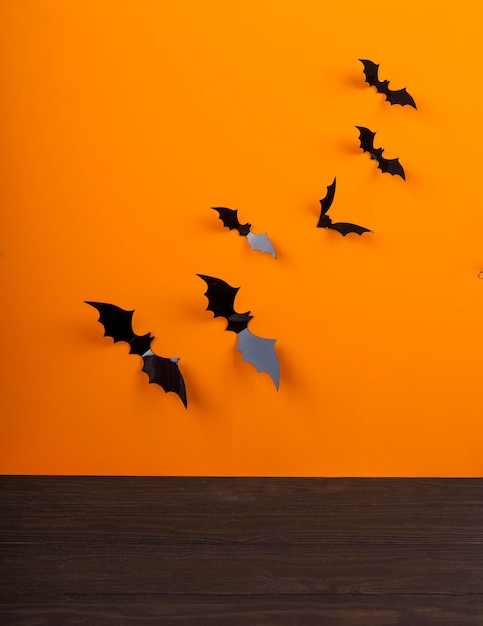 Foto mesa rústica vacía frente a fondo de telaraña, fondo naranja con murciélagos y telarañas, halloween