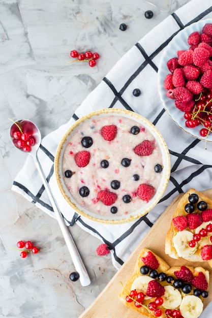 Una mesa con un saludable desayuno de verano: avena con moras, grosellas y frambuesas.