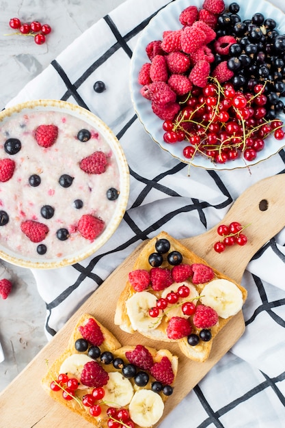 Una mesa con un saludable desayuno de verano: avena con moras, grosellas y frambuesas.