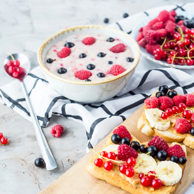 Una mesa con un saludable desayuno de verano: avena con moras, grosellas y frambuesas.