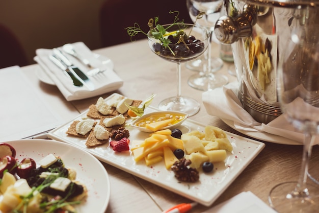 Foto mesa servida com aperitivos, talheres, copos e escarradeira para degustação de vinhos.