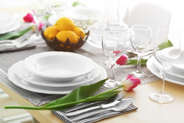 Mesa servida con platos blancos y un ramo de tulipanes