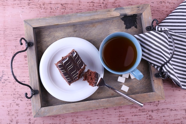 Mesa servida con una taza de té y pastel de chocolate en primer plano de fondo de madera
