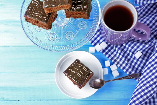 Mesa servida con una taza de té y pasteles de chocolate en primer plano de fondo azul