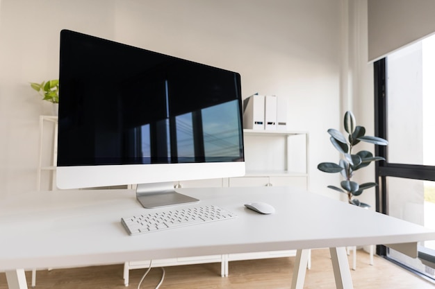 Mesa y silla blancas con monitor de computadora y archivador moderno en oficina en casa blanca