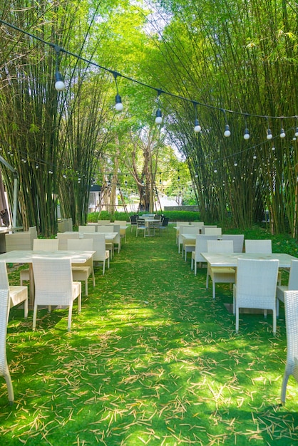 Mesa y silla de mimbre vacía en el restaurante al aire libre con jardín de bosque de bambú