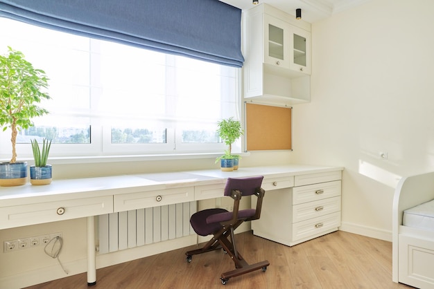 Mesa y silla de muebles blancos interiores cerca del tablero de corcho de la ventana en la pared