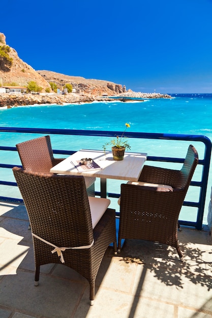 Mesa y sillas en un café frente al mar azul