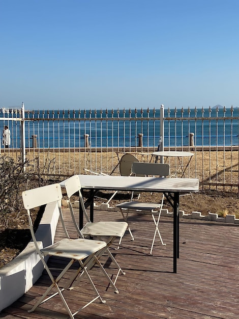 Una mesa y sillas están en una terraza con vista al océano.