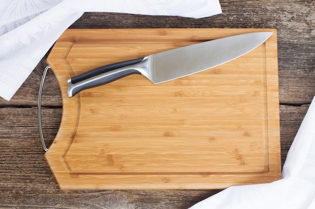 Foto mesa con tabla de cortar de madera vacía, cuchillo y servilleta de tela