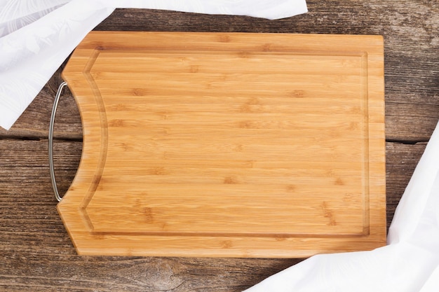 Mesa con tabla de cortar de madera vacía y servilleta de tela