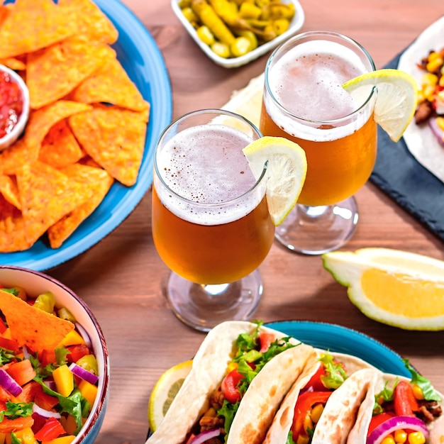 Mesa con tacos mango salsa nachos con salsa guacamole cerveza de limón para la fiesta de celebración del Cinco de Mayo Aperitivos y platos tradicionales mexicanos para la cena familiar en la mesa de madera copia espacio