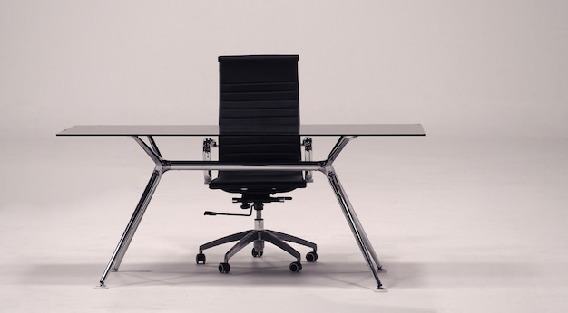 Mesa con tapa de cristal y sillón de cuero para trabajo.