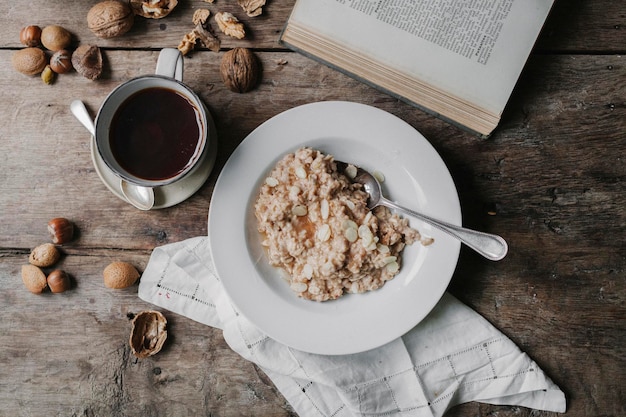 Una mesa con una taza de café con nueces de muesli y un libro abierto