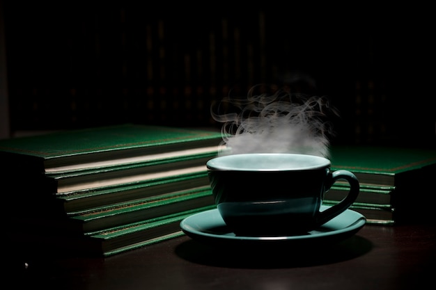 Mesa con taza verde de café hoy con libros espacio de fondo negro para texto