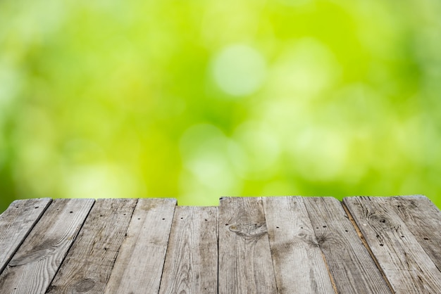 Mesa de terraza de madera vacía con follaje bokeh