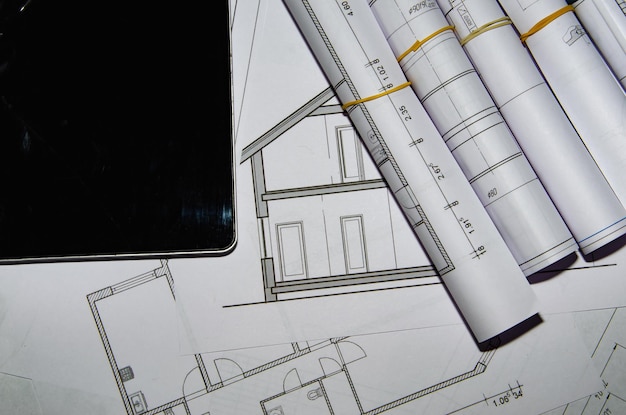 Mesa de trabajo de arquitectos con dibujos técnicos y tableta