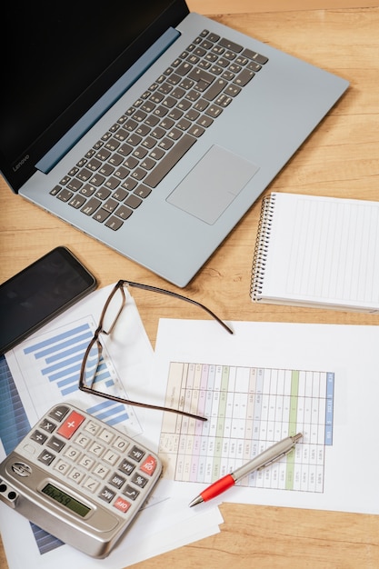 Mesa de trabajo en casa con bolígrafo, papeles, facturas, gráficos, gafas, computadora y calculadora. Concepto de trabajo en casa, cuentas corrientes, economía del hogar. Vista aérea.