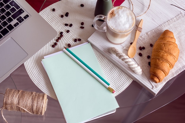 Mesa de trabajo con laptop, café y croissant.