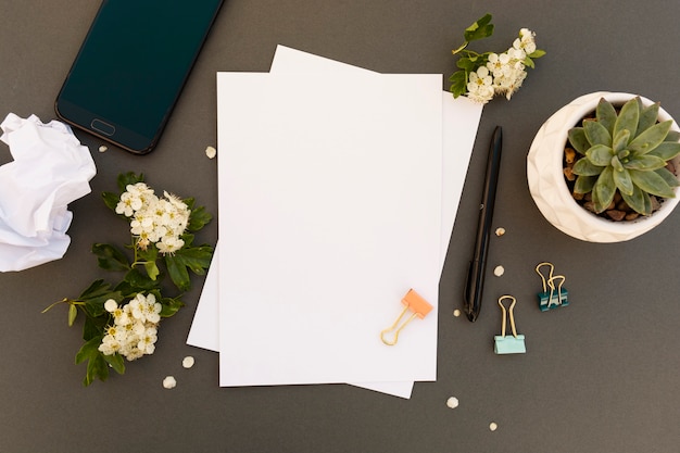 Mesa de trabajo, mesa de mock up con teléfono inteligente, pappers en blanco, marco de flores de primavera. Mesa de trabajo de oficina. Copia espacio