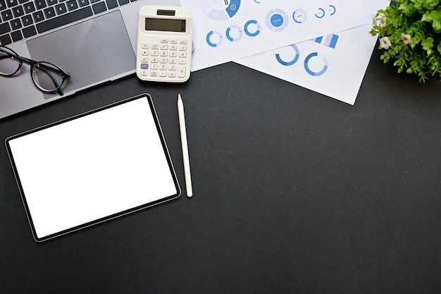 Mesa de trabajo de negocios moderna con maqueta de tableta y espacio de copia sobre fondo negro