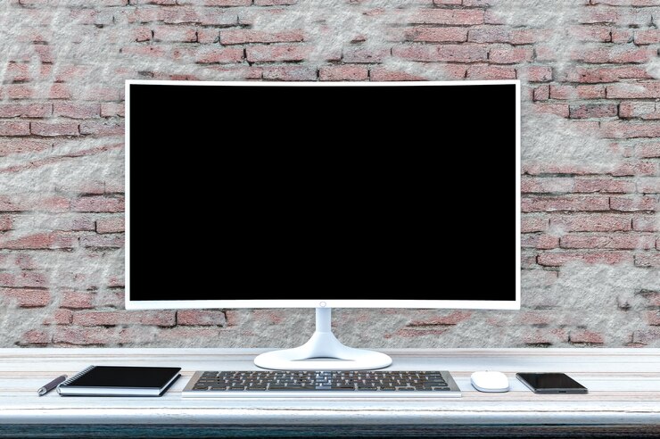 Foto mesa de trabajo con pantalla en blanco de pc en la pared de ladrillo