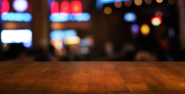 La mesa vacía de madera oscura frente al fondo abstracto y borroso del restaurante se puede usar para exhibir o montar sus productos Mock up para espacio