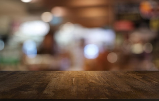 La mesa vacía de madera oscura frente al fondo abstracto y borroso del restaurante se puede usar para exhibir o montar sus productos Mock up para espacio