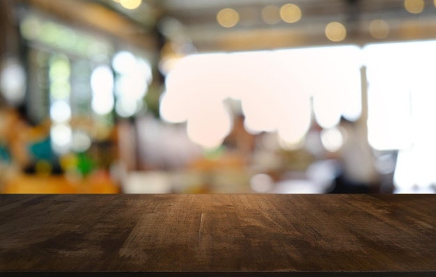 La mesa vacía de madera oscura frente al fondo abstracto y borroso del restaurante se puede usar para exhibir o montar sus productos Mock up para espacio