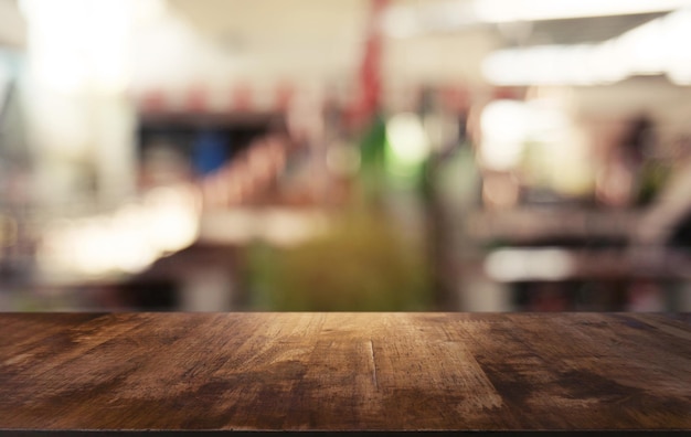Una mesa vacía de madera oscura frente a un fondo borroso abstracto del interior de la cafetería y la cafetería se puede utilizar para exhibir o montar sus productos