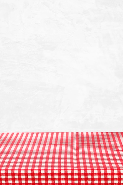 Mesa vacía con mantel de cuadros rojos y blancos sobre fondo de pared blanca