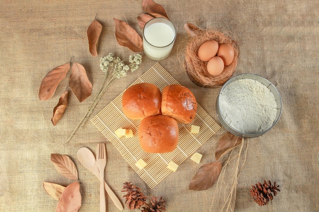 Una mesa con un vaso de leche, huevos y un plato de pan.