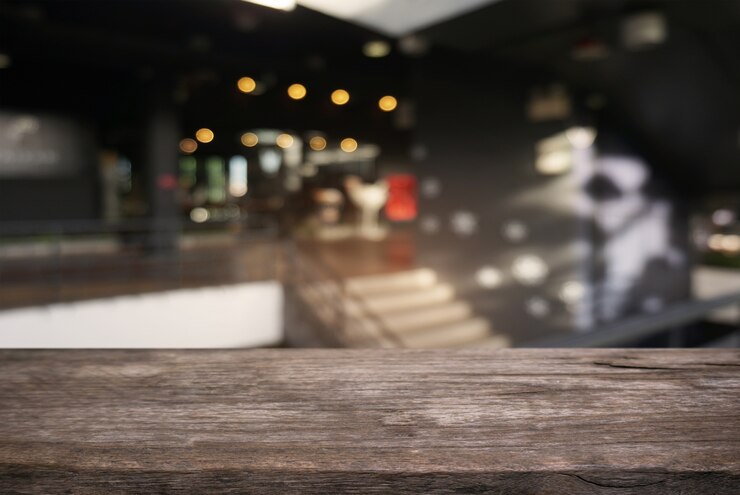 Foto mesa vazia de madeira escura em frente ao fundo abstrato borrado do interior do café e café. pode ser usado para exibir ou montar seus produtos.