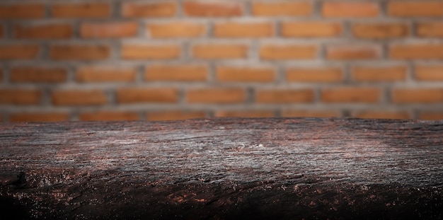 Mesa vazia de madeira, madeira rústica marrom avermelhada com holofotes. Fundo desfocado da parede de tijolos