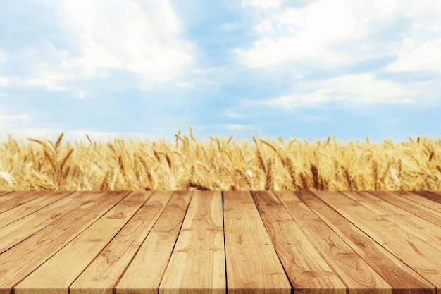 Mesa vazia de prancha de madeira para exibição de produtos com campo de trigo turva e fundo de céu azul